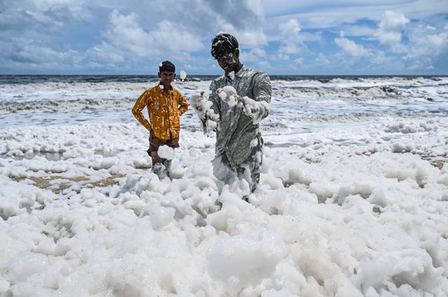 Boys play with a toxic thick layer of white foam choking the polluted Marina beach in Chennai on October 22, 2025. (Photo by R. Satish Babu/AFP Photo)