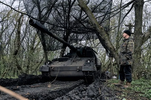 A Ukrainian soldier stands near a German self-propelled Panzerhaubitze 2000 artillery at his position on the frontline in Bakhmut, Donetsk region, Ukraine, Thursday, April 13, 2023. (Photo by Libkos/AP Photo)