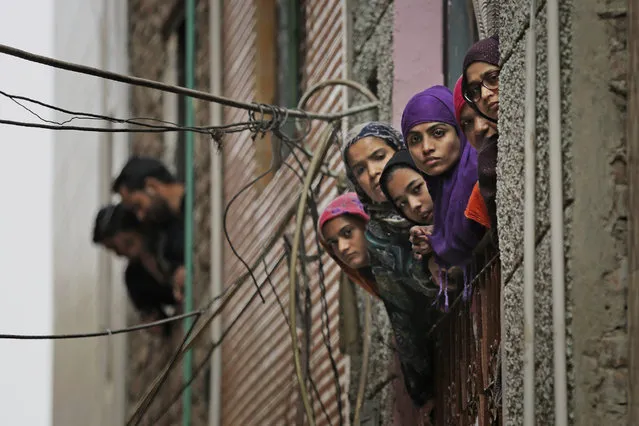 Indian Muslim women look out of a window as security officers patrol a street in New Delhi, India, Wednesday, February 26, 2020. (Photo by Altaf Qadri/AP Photo)