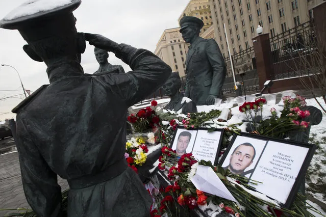 Photos of Lt.Col. Oleg Peshkov, left, and sailor Alexander Pozynich are placed at a monument to Soviet Officers with flowers and paper jet  outside Russian Army General Staff headquarters in Moscow, Russia, Thursday, November 26, 2015. Peshkov was a pilot of Russian Su-24, which was shot down by Turkish air forces and Pozynick took part in a rescue operation, both were killed. (Photo by Ivan Sekretarev/AP Photo)