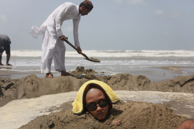 Pakistani children are seen half buried at seaside during the solar eclipse to in Karachi, Pakistan on 21,June 2020. Some Pakistani people hope that burying is ailing people during solar eclipse. (Photo by Sabir Mazhar/Anadolu Agency via Getty Images)