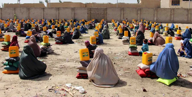 Burqa clad Afghan women sit after they received ration aid in Kandahar, Afghanistan, 05 April 2018. Ummah welfare Islamic charity organization distributed tons of ration aid to Afghans who are currently experiencing a food crisis. (Photo by Muhammad Sadiq/AFP Photo)