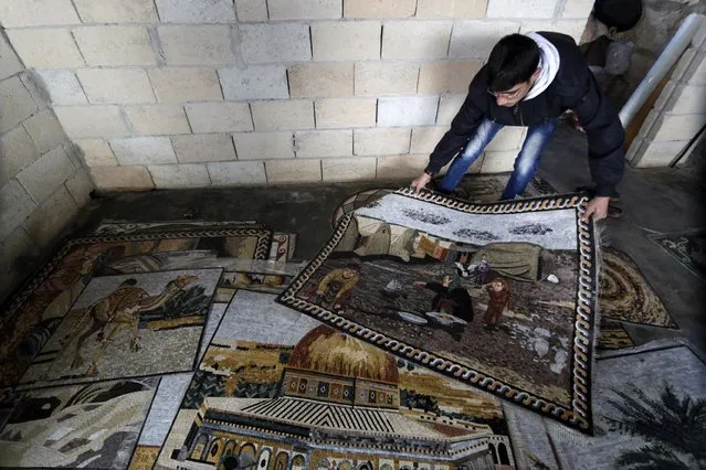 A man holds a mosaic artwork depicting life at a refugee camp, over another depicting the Dome of The Rock at a workshop in Kafranbel town in the Idlib governorate January 17, 2015. (Photo by Khalil Ashawi/Reuters)