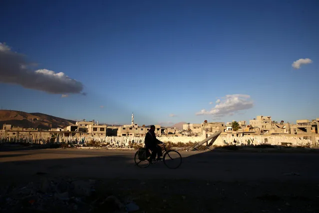 A man rides a bicycle near a cemetery in the rebel held besieged town of Douma, eastern Ghouta in Damascus, Syria November 1, 2016. (Photo by Bassam Khabieh/Reuters)