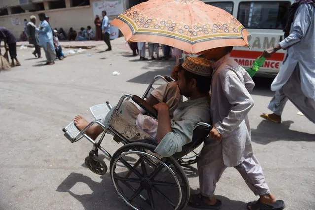 A Pakistani boy helps a patient outside a hospital during a heatwave in Karachi on May 29, 2018. Hot summer weather is prevailing in southern Pakistan and northern India with authorities issuing heatwave warnings as daytime temperatures hover around 40-44 degrees Celsius (104-111 Fahrenheit). (Photo by Rizwan Tabassum/AFP Photo)