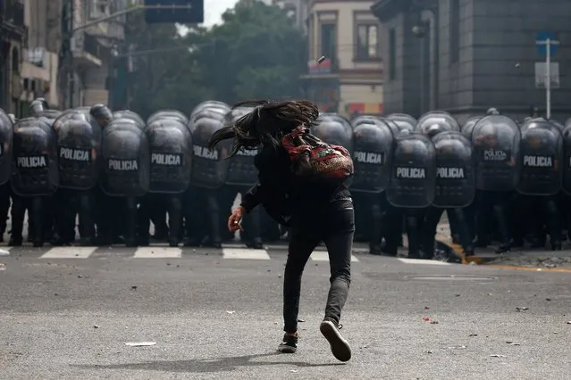 A demonstrator hurls a stone at riot police during a protest against the agreement between the Argentine government and the International Monetary Fund outside the Congress in Buenos Aires on March 10, 2022. (Photo by Marcos Brindicci/AFP Photo)