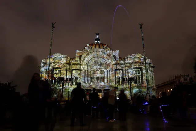 People look at the illuminated Bellas Artes palace during the International Festival of Lights in the city center of Mexico City, Mexico November 11, 2016. (Photo by Carlos Jasso/Reuters)
