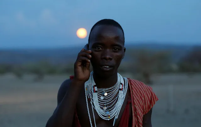 A Maasai tribesman talks on his phone as they gather to witness the rise of the supermoon in Oloika village in Shompole, Magadi near the Kenya-Tanzanian border, November 14, 2016. (Photo by Thomas Mukoya/Reuters)