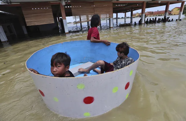 Indonesian boys sit inside a tub during a flood in Bekasi, Indonesia, Monday, February 22, 2021. (Photo by Achmad Ibrahim/AP Photo)