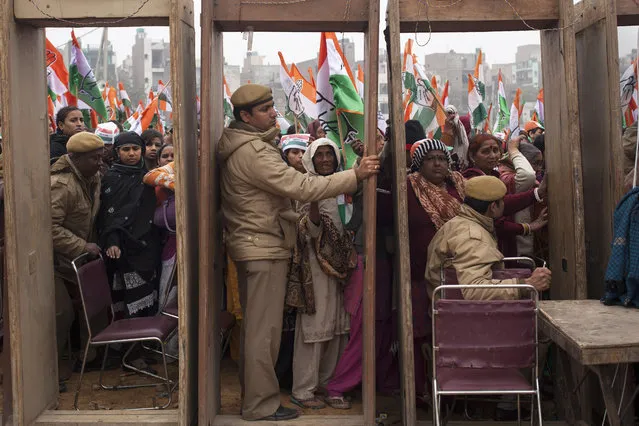 India's opposition Congress party supporters wait to enter the rally ground as policemen wait beside security gates during an election campaign rally ahead of Delhi state election in New Delhi, India, Wednesday, February 4, 2015. Delhi goes to the polls on Feb. 7. (Photo by Tsering Topgyal/AP Photo)