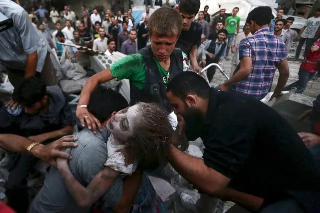 Men hold an injured girl saved from under rubble, at a site hit by what activists said was heavy shelling by forces loyal to Syria's President Bashar al-Assad in the Douma neighbourhood of Damascus June 16, 2015. (Photo by Bassam Khabieh/Reuters)