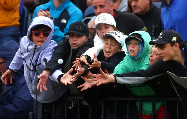 Spectators in the stand reach for a ball thrown to them at the 18th green during the second round during The 151st Open Championship in Hoylake, Britain on July 21, 2023. (Photo by Paul Childs/Reuters)