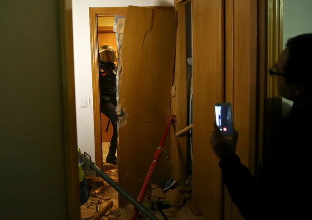 Spanish riot policemen enter the home of Jose Antonio Rojas Marcos, 32, Jessica Guabala de la Cruz, 28, and their two children, 10 and 3, breaking down the door during their eviction in Parla, outside Madrid, Spain, November 29, 2016. (Photo by Andrea Comas/Reuters)