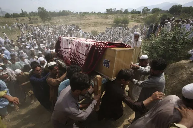 Relatives and mourners carry the casket of a victim, who was killed in Sunday's suicide bomber attack in the Bajur district of Khyber Pakhtunkhwa, Pakistan, Monday, July 31, 2023. Pakistan held funerals on Monday for victims of a massive suicide bombing that targeted a rally of a pro-Taliban cleric the previous day. (Photo by Mohammad Sajjad/AP Photo)