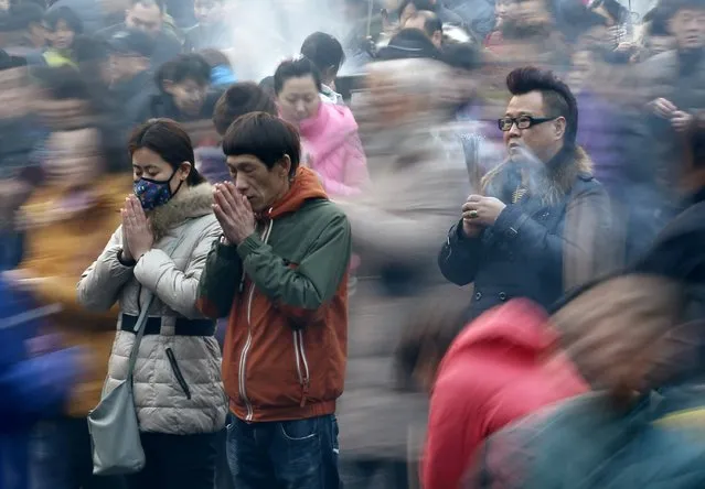 People pray for good fortune on the first day of the Chinese Lunar New Year at Yonghegong Lama Temple, in Beijing, February 19, 2015. According to the Chinese lunar calendar, the Chinese New Year, which welcomes the year of the Sheep (also known as the Year of the Goat or Ram), falls on Thursday. (Photo by Kim Kyung-Hoon/Reuters)