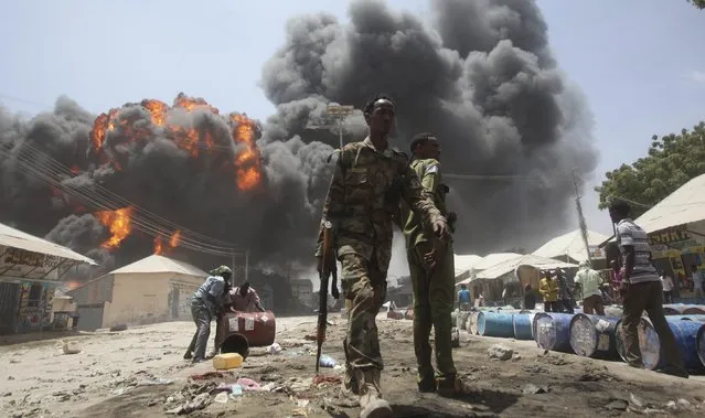 Soldiers watch as people move oil barrels away from the site of an explosion at a petrol station and storage facility near the Bakara open-air market in Somalia's capital Mogadishu, February 23, 2015. (Photo by Ismail Taxta/Reuters)