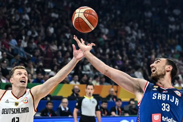 Germany's Andreas Obst (L) and Serbia's Nikola Milutinov (R) vie for the ball during the FIBA Basketball World Cup final game between Germany and Serbia in Manila on September 10, 2023. (Photo by Sherwin Vardeleon/AFP Photo)