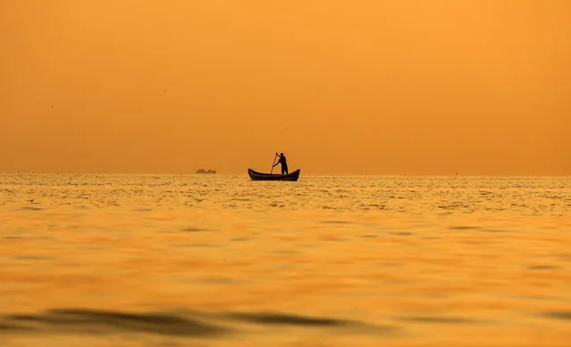 As the sun sets Indian fishermen paddle their boat along the Arabian Sea coast of Mumbai, India, 18 January 2016. (Photo by Divyakant Solanki/EPA)