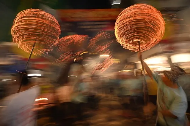 Members of the fire dragon dance team spin balls of joss sticks as the “dragon” winds through the narrow streets and houses during the Tai Hang Fire Dragon Dance in Hong Kong on September 29, 2023. Thousands of excited spectators packed the grid-like streets of a usually quiet Hong Kong neighbourhood on the night of September 29, eager for the resurrection of the city's fire dragon dance after a three-year pandemic-spurred dormancy. (Photo by Peter Parks/AFP Photo)