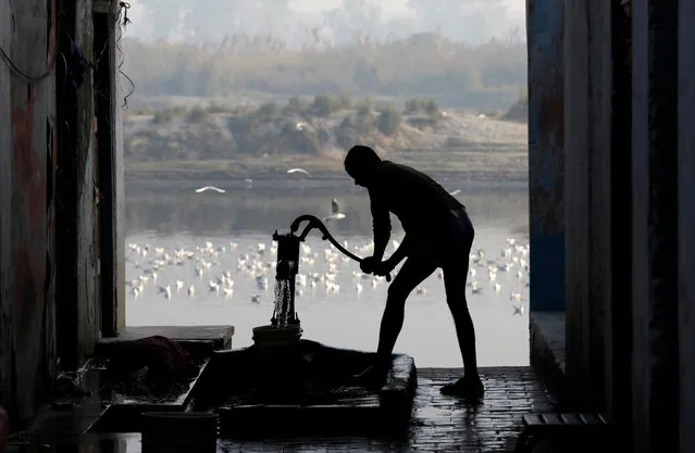 A man uses a hand-pump to collect water for bathing on the banks of the river Yamuna in New Delhi, November 21, 2018. (Photo by Anushree Fadnavis/Reuters)