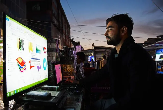 An Afghan man uses a computer at a market in Mazar-i-Sharif on October 17, 2023. (Photo by Atif Aryan/AFP Photo)