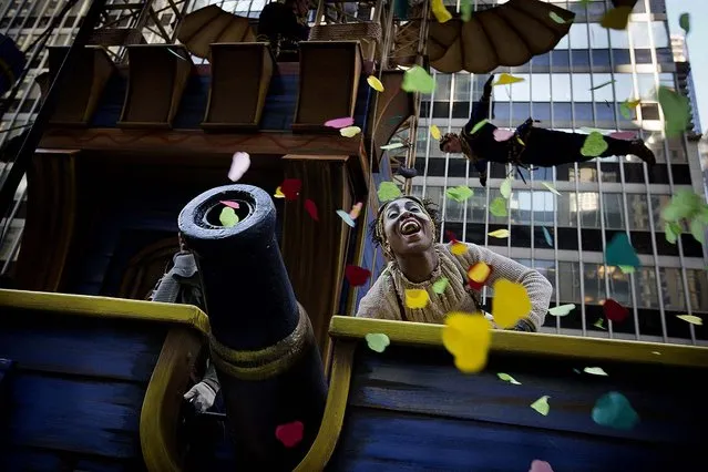 A performer on the Cirque du Soleil float cheers after firing confetti into the crowd on Sixth Avenue. (Photo by John Minchillo/Associated Press)