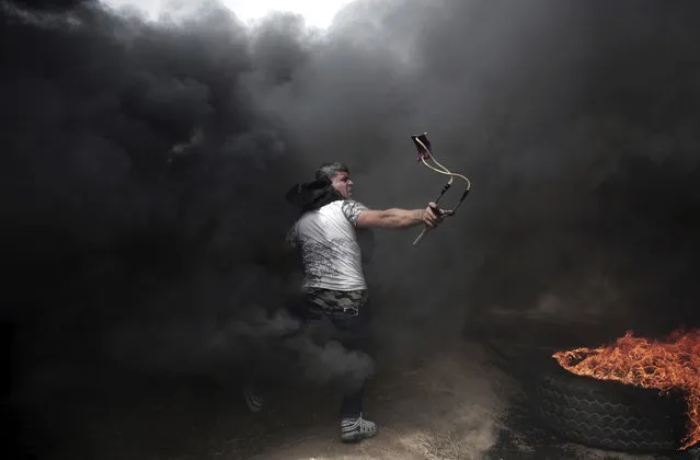 A Palestinian protester hurls stones at Israeli troops during a protest at the Gaza Strip's border with Israel, Friday, April 20, 2018, during a weekly protest on Gaza's border with Israel. (Photo by Khalil Hamra/AP Photo)
