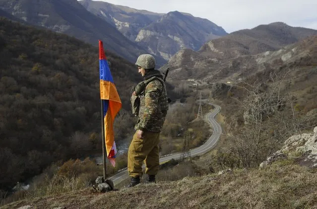 In this Wednesday, November 25, 2020 file photo, An ethnic Armenian soldier stands guard next to Nagorno-Karabakh's flag atop of the hill near Charektar in the separatist region of Nagorno-Karabakh at a new border with Kalbajar district turned over to Azerbaijan. Armenia’s Defense Ministry is reporting that three of its troops were killed and two more were wounded in clashes with Azerbaijani forces on the border between the two ex-Soviet nations. The two countries have been locked in a decades-long tug-of-war over the Nagorno-Karabakh region, and they accused each other of starting the clashes on Wednesday, July 28, 2021. (Photo by Sergei Grits/AP Photo/File)