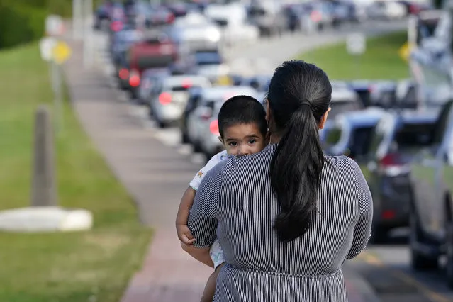 Rupinder Kaur, of Ferndale, Wash., holds her son, Gourev Singh, 7 months old, as she stretches her legs while other family members wait in the line of cars to cross into Canada at the Peach Arch border crossing Monday, August 9, 2021, in Blaine, Wash. Canada lifted its prohibition on Americans crossing the border to shop, vacation or visit but America kept similar restrictions in place, part of a bumpy return to normalcy from coronavirus travel bans. (Photo by Elaine Thompson/AP Photo)