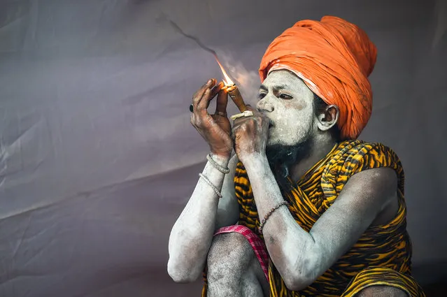 An Indian sadhu (Hindu holy man) smokes as he sits inside his tent among the Juna Akhara (a sadhu order) community at the Kumbh Mela festival in Allahabad on January 13, 2019. The festival attracts millions of Hindu pilgrims to the sacred confluence of the Yamuna and Ganges rivers over 49 days between January 15 and March 4. (Photo by Chandan Khanna/AFP Photo)