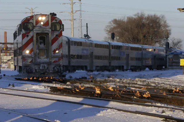 A Metra train moves southbound to downtown Chicago as the gas-fired switch heater on the rails keeps the ice and snow off the switches near Metra Western Avenue station in Chicago, Tuesday, January 29, 2019. Forecasters warn that the freezing weather Tuesday will get worse and could be life-threatening. (Photo by Kiichiro Sato/AP Photo)
