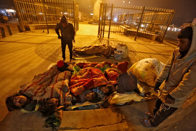 A family gather under blankets to shelter from the cold beneath a flyover in Delhi, India January 16, 2017. (Photo by Cathal McNaughton/Reuters)