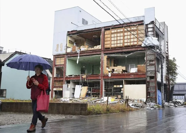 A person walks past a building with collapsed walls, as the city was hit by the earthquakes and tsunami in Nanao, Ishikawa prefecture, Japan Wednesday, January 3, 2024. A series of powerful earthquakes that hit western Japan left multiple people dead Wednesday, as rescue workers fought to save those feared trapped under the rubble of collapsed buildings.(Photo by Kyodo News via AP Photo)