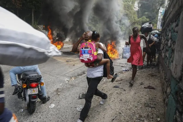 People walk past burning tires during a protest against Haitian Prime Minister Ariel Henry in Port-au-Prince, Haiti, Monday, February 5, 2024. (Photo by Odelyn Joseph/AP Photo)
