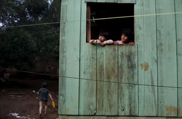 Guarani Indian children look from a window of their house in the village of Pyau at Jaragua district, in Sao Paulo April 28, 2015. (Photo by Nacho Doce/Reuters)