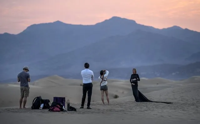With extreme record breaking high temperatures reaching 135 degrees fahrenheit during the weekend, a photographic shoot is done during the cooler temperature of 109 degrees fahrenheit during sunrise at Mesquite Flat Sand Dunes in Death Valley National Park, California Sunday July 11, 2021. (Photo by Melina Mara/The Washington Post)