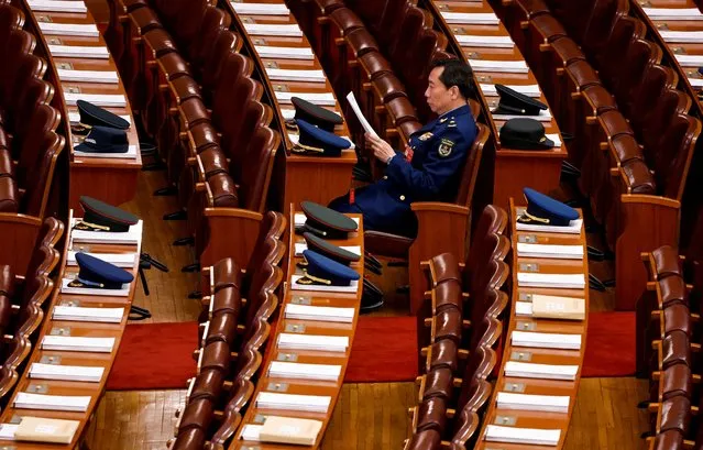 A military delegation member reads reports inside the Great Hall of the People on the day of the opening session of the NPC, in Beijing, China on March 5, 2024. (Photo by Tingshu Wang/Reuters)