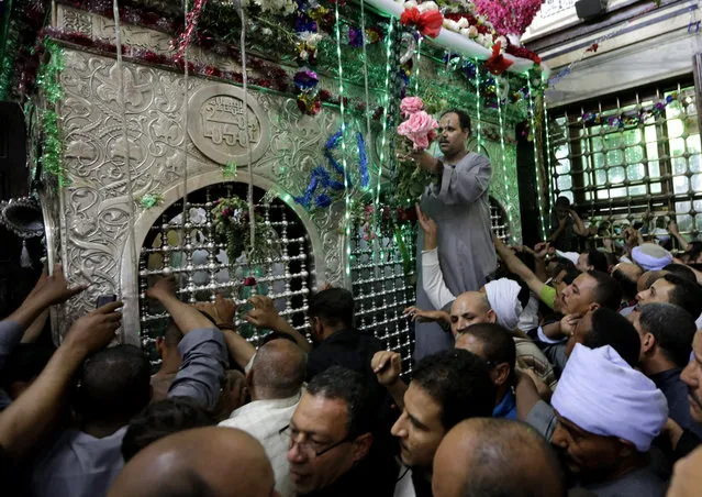 In this photo taken Tuesday, May 12, 2015, an Egyptian decorates the shrine of Sayyeda Zeinab with flowers, as hundreds celebrates a religious festival, or Moulid, which commemorates of the birth of Muslim Prophet Muhammad's granddaughter Sayyeda Zeinab, inside the mosque and shrine named for her, in Cairo, Egypt. (Photo by Amr Nabil/AP Photo)