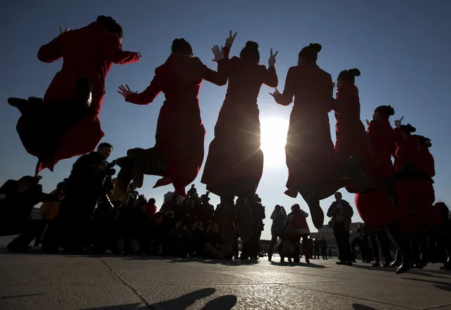Chinese hostesses who serve the delegates of the National People's Congress jump as they pose for photographers in front of the Great Hall of the People during the opening session of the annual National People's Congress in Beijing, China, Wednesday, March 5, 2014. (Photo by Andy Wong/AP Photo)