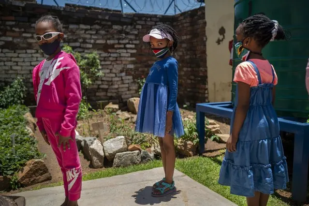 Pupils wearing masks line up to enter their classroom at the Kgololo Academy on “Spirit Day” in Johannesburg's Alexandra township Tuesday November 30, 2021. Despite global worry, doctors in South Africa are reporting patients with the COVID-19 omicron variant are suffering mostly mild symptoms so far. But they warn that it is early and most of the new cases are in people in their 20s and 30s, who generally do not get as sick from COVID-19 as older patients. (Photo by Jerome Delay/AP Photo)