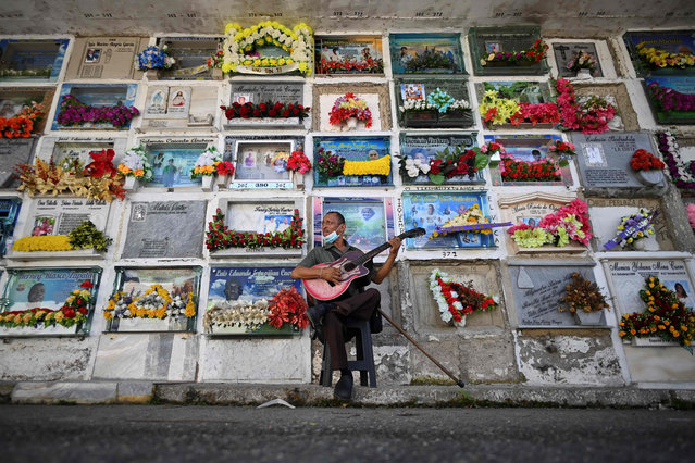 Javier Giraldo, 57, a musican who has played his guitar for 30 years in burials, is seen at the cemetery in Buenaventura, Colombia, on February 10, 2021. Since December, 2020, Buenaventura has been suffering a blood and fire dispute between members of the La Local armed group, which split into two substructures known as Shotas and Espartanos, that are now facing each other to death for the control of drug trafficking. (Photo by Luis Robayo/AFP Photo)
