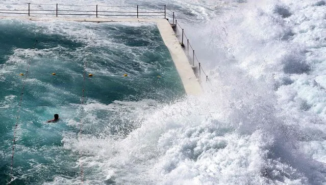 A swimmer at Bondi's ocean pool watches as a big wave pours into the pool as large seas pound the coast at Bondi Beach in Sydney on March 6, 2017. (Photo by William West/AFP Photo)