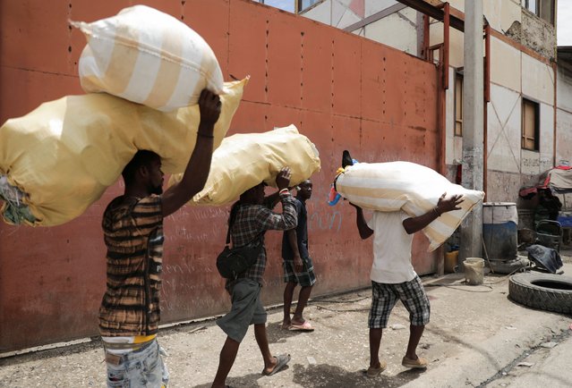 Workers carry goods as they walk, in Port-au-Prince, Haiti on May 1, 2024. (Photo by Ralph Tedy Erol/Reuters)