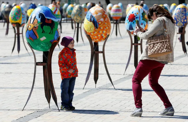 A woman takes pictures of a boy in front of a traditional Ukrainian Easter egg “Pysanka”, installed as part of the upcoming celebrations of Easter, in central Kiev, Ukraine, April 29, 2016. (Photo by Valentyn Ogirenko/Reuters)