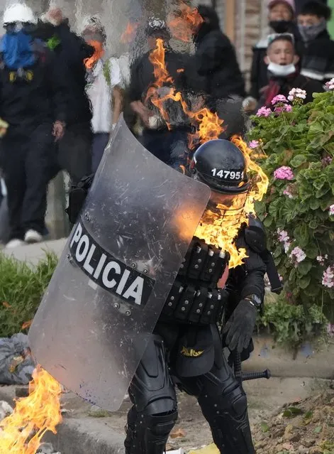 A police officer is engulfed in flames after he was hit with a petrol bomb during an anti-government protest triggered by proposed tax increases on public services, fuel, wages and pensions in Bogota, Colombia, Monday, June 28, 2021. (Photo by Fernando Vergara/AP Photo)