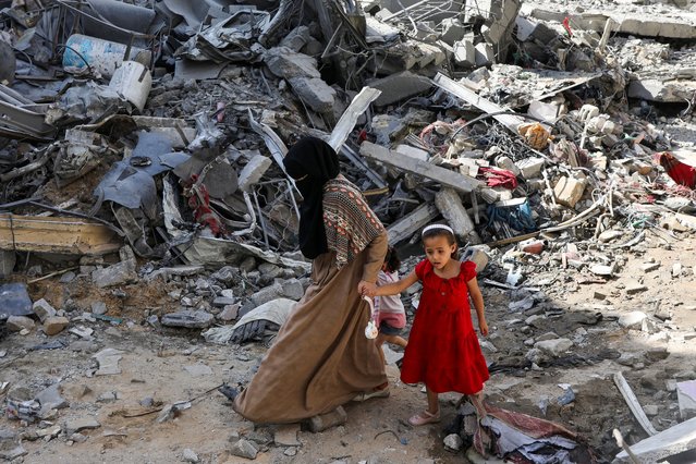 A woman and child walk among debris, aftermath of Israeli strikes at the area, where Israeli hostages were rescued on Saturday, as Palestinian death toll rises to 274, amid the Israel-Hamas conflict, in Nuseirat refugee camp in the central Gaza Strip on June 9, 2024. (Photo by Abed Khaled/Reuters)
