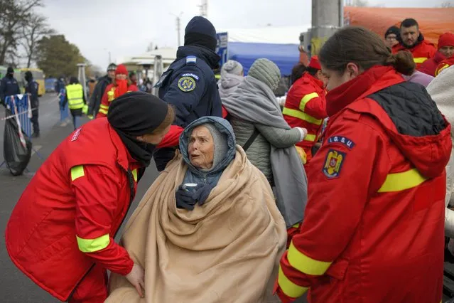 Emergency Situations Department employees talk to wheelchair user Katia, 90 years-old, a refugee fleeing the conflict from neighbouring Ukraine at the Romanian-Ukrainian border, in Siret, Romania, Saturday, March 5, 2022. (Photo by Andreea Alexandru/AP Photo)