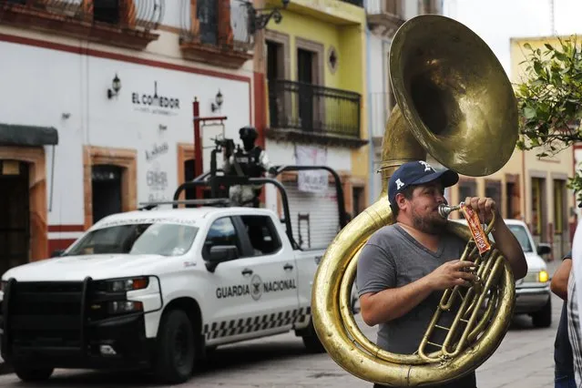 A man plays the tuba as the National Guard patrols downtown Jerez, Zacatecas state, Mexico, Friday, July 16, 2021. For years, much of Mexico's violence was focused along its northern border in cities like Tijuana, Ciudad Juarez and Nuevo Laredo. Now Zacatecas, including in the state capital of the same name, awaken everyday to the violence. (Photo by Marco Ugarte/AP Photo)