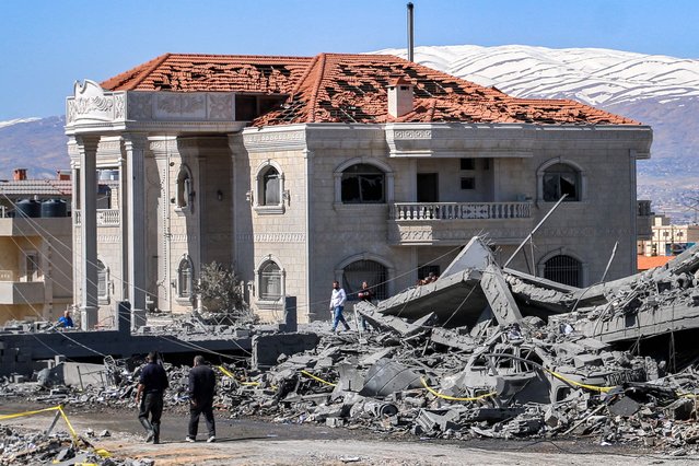 People walk past a damaged building in the aftermath of an overnight Israeli airstrike on the city of Baalbek in east central Lebanon on March 12, 2024. Israeli air strikes on March 11 near Lebanon's eastern city of Baalbek killed one person, in the second raid on the Hezbollah stronghold since cross-border hostilities began. The Israeli military confirmed its jets had hit two sites belonging to "Hezbollah's aerial forces" in retaliation for strikes on the occupied Golan Heights over several days. (Photo by AFP Photo)