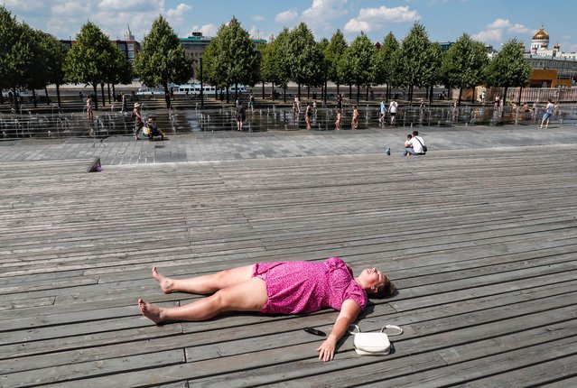 A woman sunbaths during a hot day in Moscow, Russia, 02 July 2024. According to the leading specialist of the Phobos weather center, Evgeny Tishkovets, 28 temperature records were recorded in Russia on 02 July 2024. In downtown Moscow, the air heated up to plus 32.1 degrees Celsius. (Photo by Yuri Kochetkov/EPA/EFE)